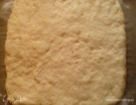 Противень смазать сливочным маслом и присыпать мукой (я просто выложила на него бумагу для выпечки и сделала то же самое с ней). Тесто выложить на противень и сформировать из него квадратный пласт. 