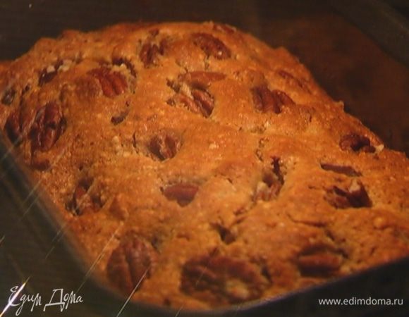 Продолговатую форму для выпечки смазать растительным маслом, выложить тесто, вдавить в него кусочки шоколада, сверху разложить орехи, слегка прижав их.