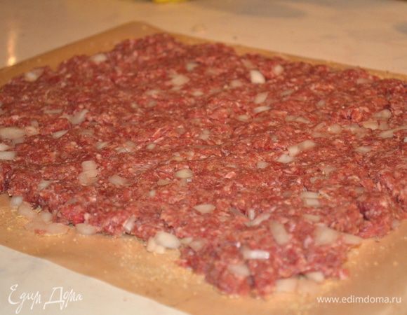 на сухари выкладываем фарш в форме прямоугольника толщиной 1 см и длиной как у вашей формы для выпечки. То есть длина формы равна длине пласта из фарша - ЭТО ВАЖНО! И с обеих сторон нужно оставить свободные края у пергамента, так будет удобнее заворачивать в рулет. 