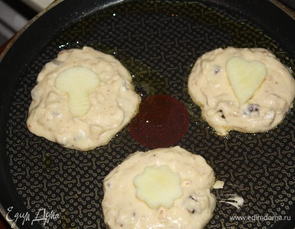 На разогретую сковороду наливаем оливковое масло и выкладываем ложкой оладушки. Фигурку из яблока кладем в серединку оладушки и слегка вдавливаем. Обжариваем по 3 - 4 минуты на каждой стороне.