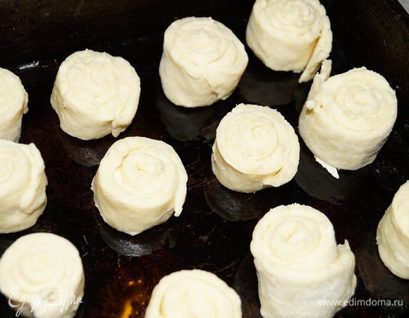 Разделите тесто на несколько частей, каждую часть раскатайте в пласт и сверните рулетом, нарежьте на небольшие кусочки (шириной примерно 2 см). Выложите их на противень, смазанный маслом, на небольшом расстоянии друг от друга.