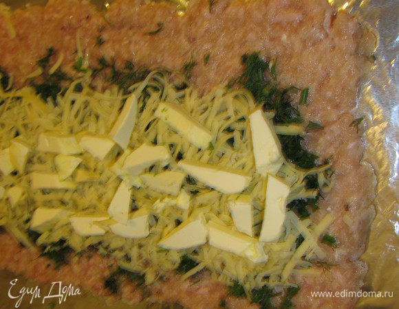 Сыр натираем на крупной терке и выкладываем поверх зелени.
Масло, предварительно замороженное, нарезаем кусочками и выкладываем поверх зелени и сыра. При помощи фольги сворачиваем рулет.