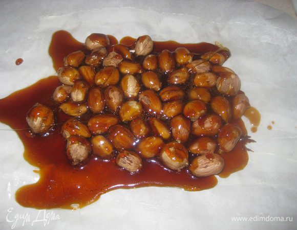 Готовим ореховое пралине: смазываем маслом пергаментную бумагу и выкладываем сверху фундук. Сахар высыпаем в кастрюльку, добавляем 1 ст.л. воды и ставим на средний огонь. Сахар начнет плавиться и  сделается коричневого цвета. Нужно быть внимательным, чтобы сахар не сгорел, а только образовалась карамель. Когда сахар станет светло-коричневого цвета и полностью расплавится, быстро выливаем карамель на фундук.