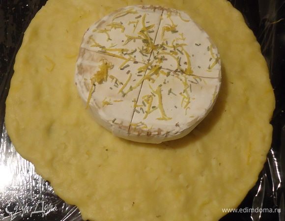 В центр круга выложим камамбер. На камамбере делаем неглубокий крестообразный надрез. Посыпаем половиной цедры и розмарина.