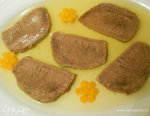 На застывшее желе выложите украшения из моркови и зелени, лимон — на кусочки мяса. Аккуратно влейте немного бульона, только для того, чтобы зафиксировать украшение, и вновь поместите блюдо в холодильник. Затем влейте нужное количество бульона, полностью покрыв им мясо и морковь. Оставьте в холодильнике до полного застывания.