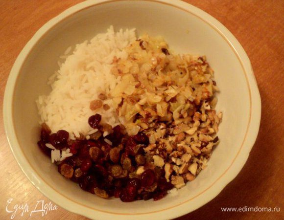 Рис отварить, слить воду. Изюм и вяленную клюкву промыть горячей водой и добавить к рису. Туда же добавить дробленные орехи и пассированный на сливочном масле  мелко порезанный лук.
