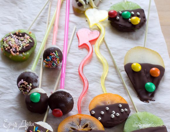 Достаем фрукты из морозилки, окунаем в шоколад и украшаем драже, бусинками, посыпками. Накройте глазированные фрукты пленкой и уберите в морозильную камеру, где они и будут храниться вплоть часа Х. 
 Внимание! Фрукты тают очень быстро, поэтому советую не доставать их заранее, а вручить в руку каждому ребенку. 10 минут детишкам вполне хватит, чтобы скушать ломтик, но на большее не рассчитывайте.
 ЗЫ. Лучше всего повели себя хурма, банан и виноград. Киви потек быстрее всех, но фотосессию выдержал. Груша оказалась хоть и вкусной, но слишком большой и все время норовила сползти с палочки. Ни один из фруктов свой вкус после заморозки не потерял.