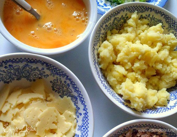 Картофель разминаем вилкой.Тунец отцеживаем от лишней жидкости.Можно картофель перемешать с тунцом.Лук и петрушку режем.Сыр рвем на кусочки