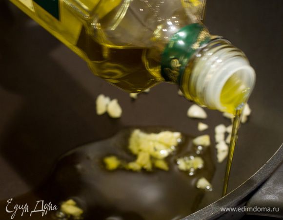 В глубокую сковороду налить оливковое масло и спассеровать в нём зубочки чеснока.