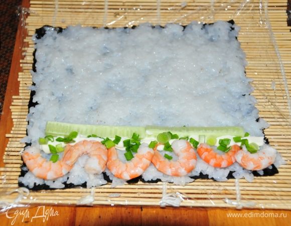 Второй ролл - Футомаки с креветками:
Как и в первом случае на нории выкладываем рис. С краю начинка: креветки, тонкая полосочка майонеза, зелёный лук и брусочки огурчика. Сворачиваем точно так же. И разрезаем на 8 частей.
