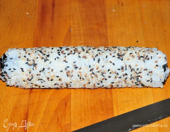 Сверху ролл обсыпать кунжутом (у меня смесь белого, коричневого и чёрного) или можно обмазать икрой летучей рыбы. И порезать на 8 кусочков.