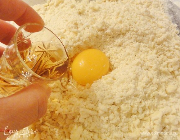 Добавьте желток, коньяк, холодную воду и замесите мягкое тесто. 