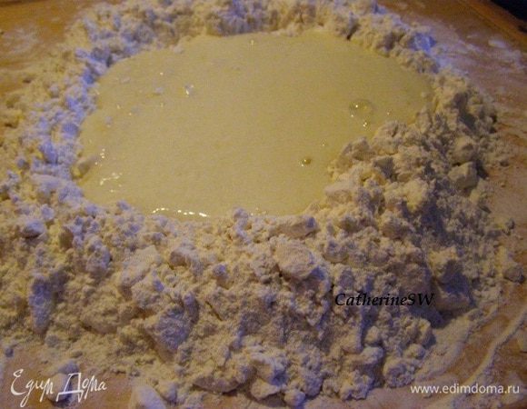 В муке сделайте углубление, влейте в него яично-сметанную смесь.