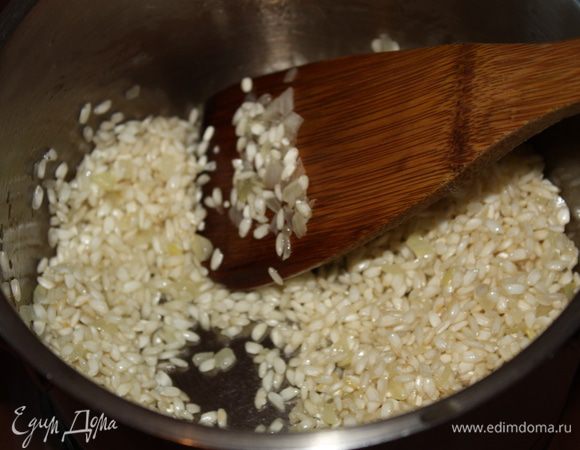 Добавить рис и обжаривать на умеренном огне,пока рис не станет почти прозрачным. Посолить по вкусу. Увеличить температуру,влить вино и подождать пока оно выпарится.