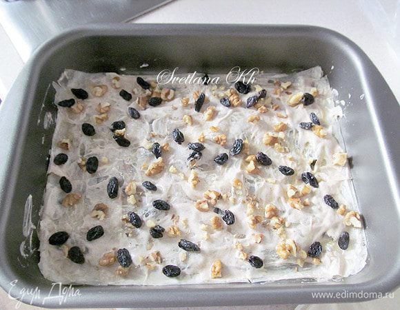 Смазать тесто слегка взбитым белком, разложить сверху орехи и изюм.