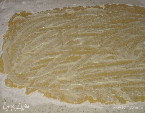 Достаем тесто из холодильника и делим его на 2 части. Работаем сначала с первой. Присыпав стол мукой, раскатываем тесто в большой прямоугольник. Смазываем поверхность половиной сливочного масла. Затем выкладываем ягоды варенья без фанатизма. Если положить слишком много, то в процессе формирования булочек - выпечки варенье вытечет и пропадет. Сверху присыпаем половиной заготовленных орехов.