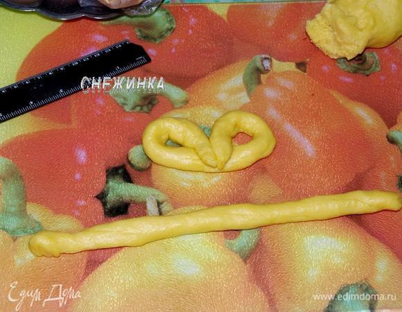 Охлажденное тесто разделите на кусочки. Раскатайте кусочек в виде колбаски, поделите на жгутики около 20 см длиной и около 1 см шириной. Загните «крендельком», для этого каждый конец жгутика заверните к середине, чтобы образовались колечки, концы при этом должны немного выступать снизу.