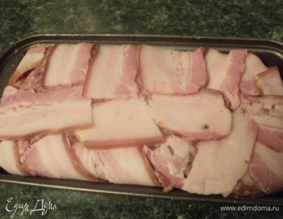 Выложить  вторую половину фарша, хорошо уплотнить и накрыть сверху свешивающимися полосками грудинки.
