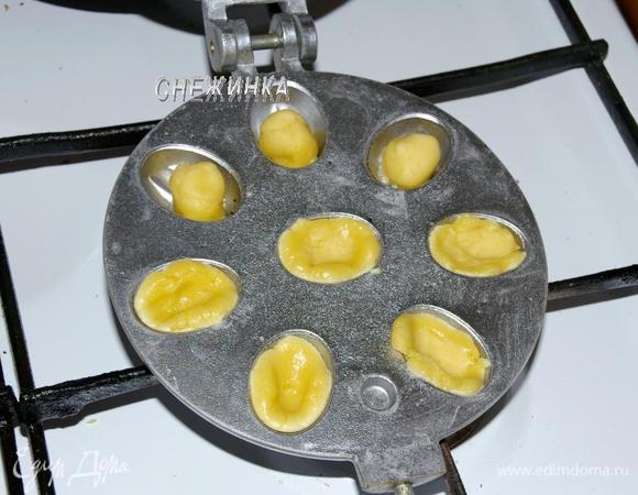 Теперь можно заняться выпечкой орешков. Форму, как и в предыдущем варианте, разогрейте с двух сторон. Для этого печенья форму смазывать не нужно, тесто прилипать не будет. Отщипните от теста маленькие шарики, немного разомните под размер выемки. Накройте второй половиной формы и жарьте на огне. Помните, что половинки орешков пекутся быстро, в этом варианте тесто получается тонкое, уже через 1–1,5 минуты нужно переворачивать форму, поэтому лучше не отвлекаться. Проверяйте, приоткрыв форму.