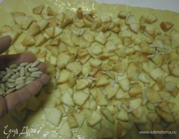 Теперь очередь начинки. Яблоки очистить и нарезать кусочками. Выложить на тесто, оставляя свободными края . Сверху посыпать кедровыми орешками.