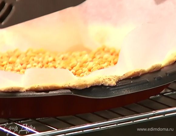 Охлажденный корж выстелить бумагой для выпечки, заполнить горохом или фасолью и отправить в разогретую духовку на 15 минут.