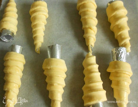 Положите трубочки с тестом на сбрызнутый холодной водой противень и, смазав яйцом, выпекайте 20–25 минут при температуре 240–250°C. Мне потребовалось 15 мин при 200°C с конвекцией. Обрезки теста также выпекайте  до светло-коричневого цвета, а затем раскрошите для посыпки. Трубочки из слоеного теста должны быть легкими и румяными. Вынув изделия из духовки, удалите жестяные или бумажные трубочки.