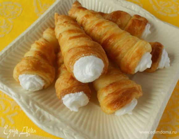 Переложите белковый крем в кондитерский мешок и наполните трубочки. На крем нанесите посыпку. Трубочки выложите на блюдо и присыпьте сахарной пудрой через ситечко. Подавайте сразу же!