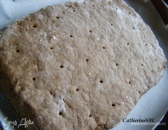 Переложите на лист, покрытый пергаментом, сделайте проколы зубочисткой, верх смажьте молоком.