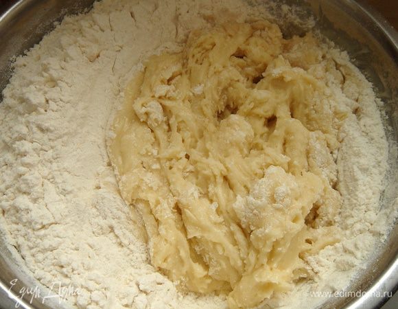 Соедините муку и соду. Смешайте муку с масляной смесью. Тесто получается мягким и не липнет к рукам.