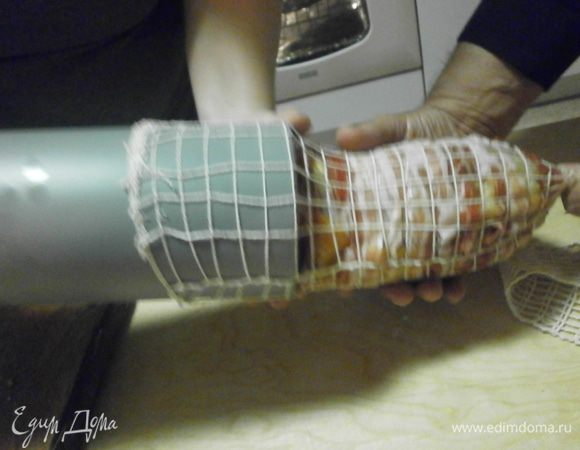 Завязать свободный конец сетки и призвав на помощь ещё пару рук, прогоняем рулет через трубу прямиком в сетку. Чтобы определить необходимую длину сетки необходимо приложить сетку к рулету и оставить с обеих сторон приблизительно по 5 см. При использовании шпагата, отмеряется 11 длин рулета.