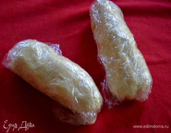 Добавить творожную смесь к муке и перемешать, затем немного перемешать руками и собрать в комок. Выложить тесто на стол, сформировать брусок, разрезать на 2 части.
Каждый кусок в прямоугольник толщиной 1-1 1/2 см, завернуть в плёнку. Положить в холодильник для охлаждения.