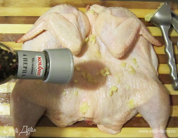 Чеснок очистить и измельчить с помощью чеснокодавилки. Натереть цыпленка внутри и снаружи солью, чесноком, приправить перцем.