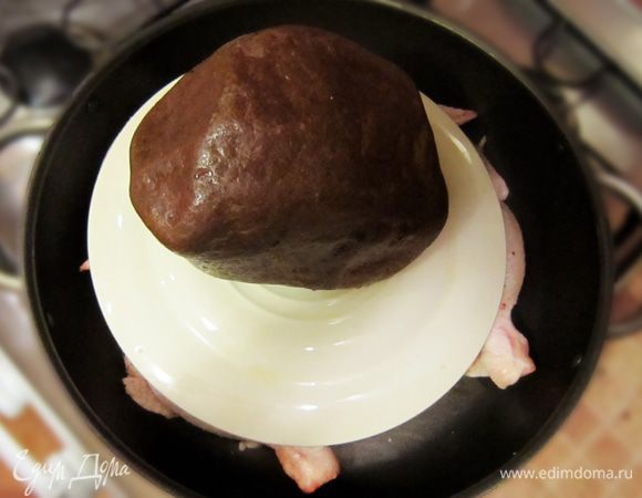 Поставить на него гнет (например, на тарелку сверху поставить камень, кирпич или кастрюлю, наполненную водой). Готовить на среднем огне. Через 15 минут перевернуть цыпленка на другую сторону, вновь поставить гнет и жарить еще 15 минут.