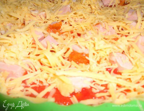 Сверху выложить равномерно порезанную кубиками ветчину и присыпать обильно тертым сыром.