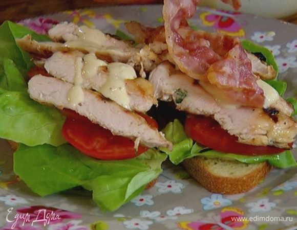 Смазать тосты частью заправки, выложить на них листья салата, кружки помидора, курицу, полить оставшейся заправкой, а сверху положить бекон.