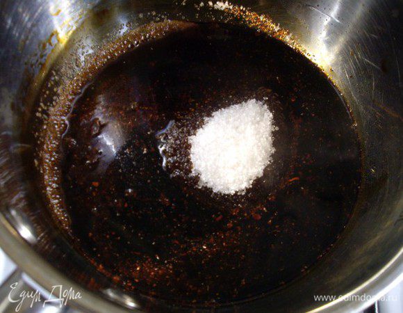 Сахар должен потемнеть и стать темно-коричневым. Дождаться когда сахар перестанет бурлить. Влить кипяток.
Круговыми движениями кастрюли смешать воду с карамелью, получится очень темная жидкость, почти черного цвета.