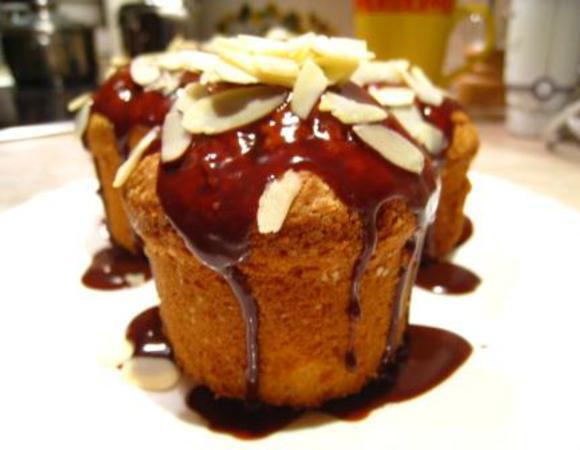 Яйца взбить с сахаром в светлую пышную массу. Просеять муку. Аккуратно перемешать. Влить 50 г растопленного масла, перемешать. Делайте это осторожно, чтобы масса не осела. Распределить тесто по формочкам на 2/3. Добавить шоколадные дольки. 