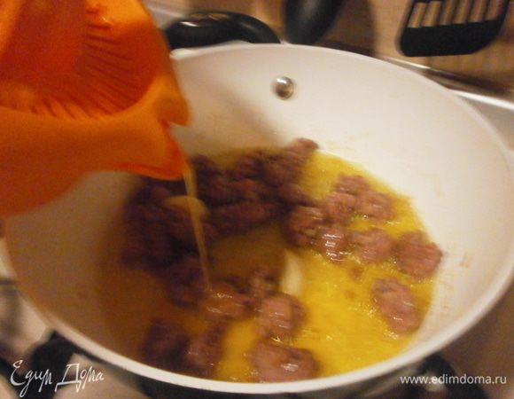 Пока варится паста, на сковороду наливаем немного оливкового масла, лук нарезать  мелко, слегка обжарить вместе с чесноком. Чеснок затем убрать. С колбасок снять плёнку и мелкими кусочками выложить на сковороду. Слегка обжарить со всех сторон. С апельсина натереть цедру на тёрке, держать отдельно.Выдавить сок с апельсина и полить колбаски. Оставить тушиться 5 минут.