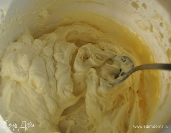 Размягченное масло взбить миксером так, чтобы получилась пышная белая масса, продолжая взбивать вливать небольшими порциями сироп.