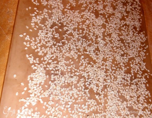 Вырезаем бумагу для выпечки по размеру формы и густо насыпаем сезам (или муку).