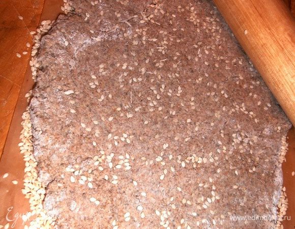 Аккуратно разминаем в руках половину тестоа (если нужно - добавляем муки, мне немного понадобилось, чтобы не прилипало к рукам, но брала уже обычную) и раскатываем пласт (чем тоньше - тем хрустящее получится!) Сверху я тоже немного сыпанула сезама!