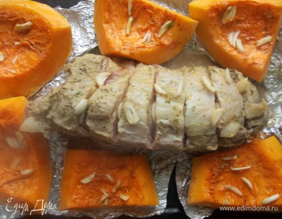 Через час запекания, достать мясо и развернуть фольгу. Выложить рядом с мясом тыкву. По сыпать мелко порезанным чесноком и поставить запекаться еще на пол часа.