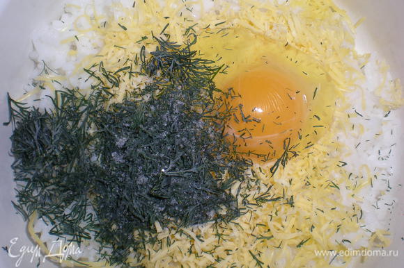 В слегка остывший рис добавить одно яйцо, половину натертого твердого сыра, укроп.