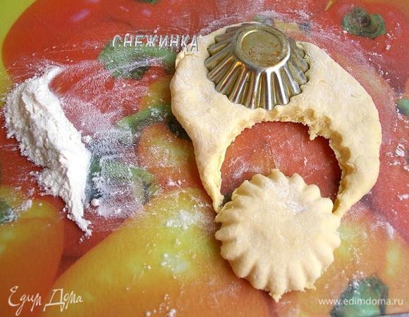 За время пребывания в холоде тесто станет более плотным и немного тягучим. Отделяем небольшое количество теста на рабочую поверхность, густо припыленную мукой. Раскатываем до 1 см. в высоту, можно просто размять руками, что я и делала. Металлической формочкой для кекса с волнистыми краями вырезаем коржики. Проделываем те же операции с остальным тестом.