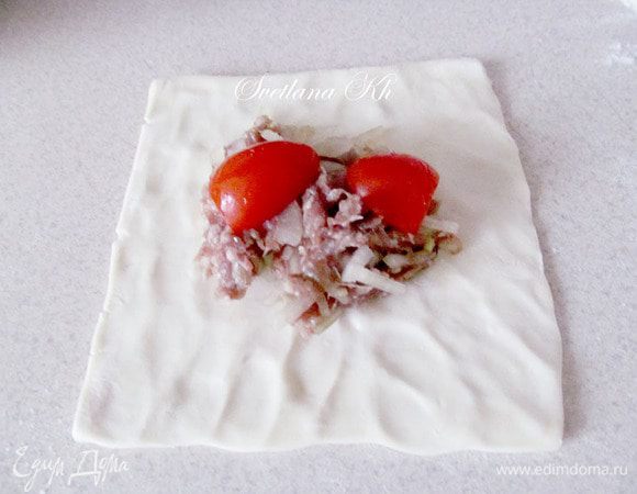Готовый квадратик теста размять таким образом, чтобы серединка осталась толстой, а края были тоньше. Выложить в центр фарш и разрезанный помидор. 