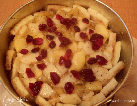 Дно формы для выпечки застелить бумагой для выпечки,  хорошо смазать дно и бока сливочным маслом. Бока и дно выложить замоченными ломтиками хлеба, поджаренной стороной к стенкам формы. Выложить половину яблочной начинки, посыпать вяленой клюквой. На начинку выложить замоченные в сливках ломтики хлеба (не поджаренные), полить немного яично-сливочной смесью, полить растопленным сливочным маслом. Выложить вторую часть яблочной начинки, клюкву.