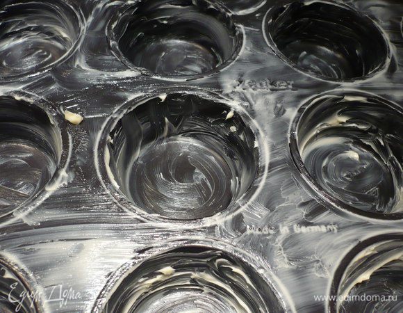 Смазываем форму для выпечки маффинов полностью маслом.