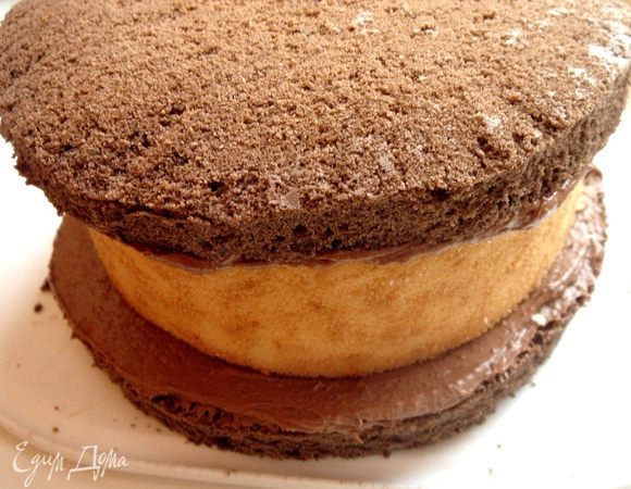 Смазать рулет кремом и накрыть вторым шоколадным коржом. Обмазать торт кремом со всех сторон.