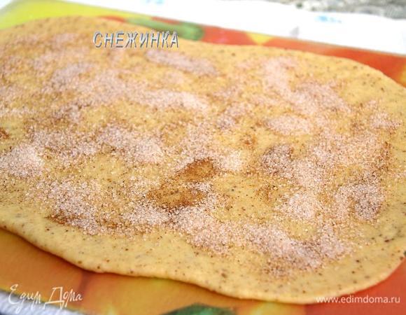 Для посыпки смешиваем сахар с корицей. Поднявшееся тесто обминаем, делим на 2 части, чтобы удобнее раскатывать. Раскатываем одну часть в прямоугольник, толщиной около 4 мм. Равномерно посыпаем сахаром с корицей.