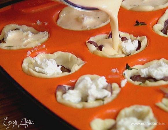 В выемки с тестом выложить понемногу обжаренного лука и нарезанной феты, а затем залить яично-сливочной массой так, чтобы она покрыла лук и сыр.